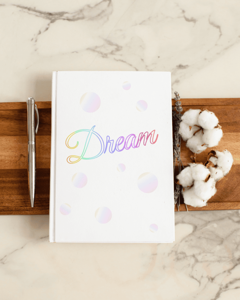 Dream gradient journal mock-up with rainbow script text on cover. Graphic design.