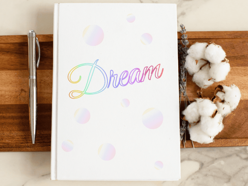 Dream gradient journal mock-up with rainbow script text on cover. Graphic design.